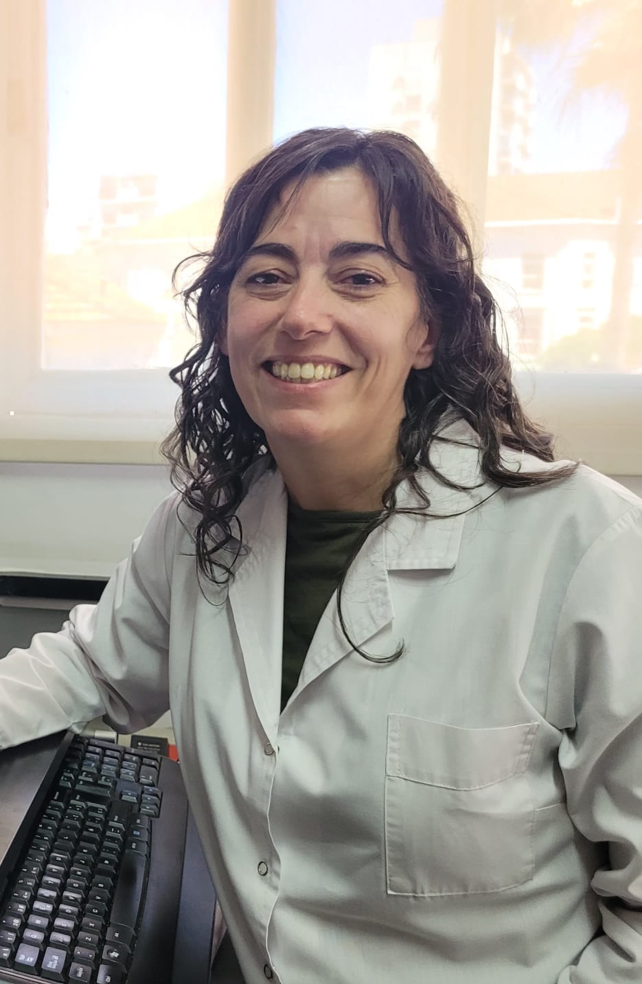 Smiling scientist in lab coat at keyboard
