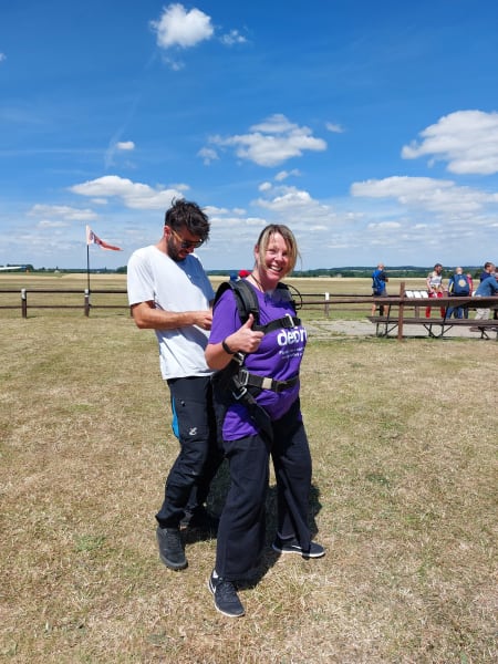 Woman from AVEVA being strapped with parachute for skydive