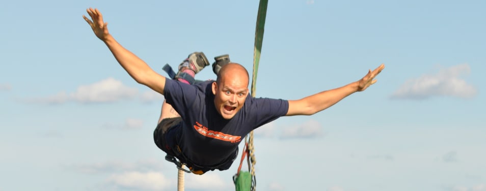 Man screams as he bungee jumps with his arms stretched out