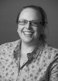 A black and white photo of a smiling person wearing glasses 