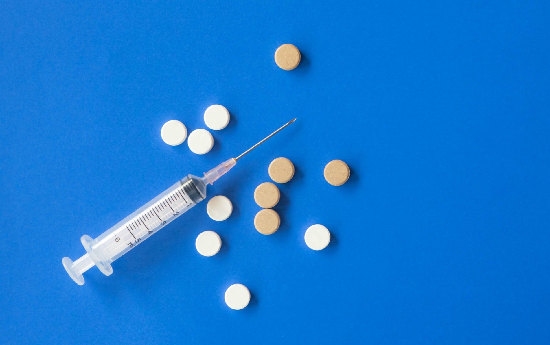 Syringe and tablets on a blue background