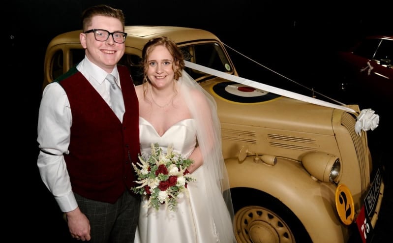 Heather and Ash on their wedding day with a classic car in the background.