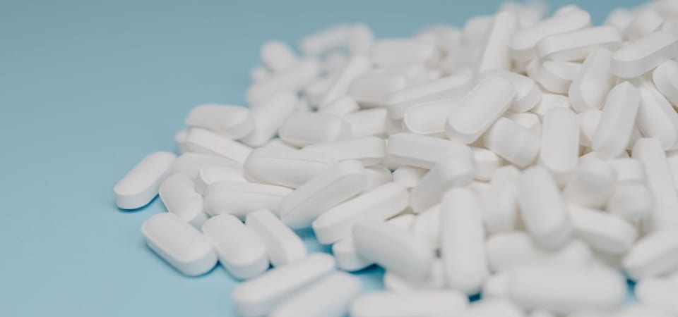 A pile of white pills on a light blue background