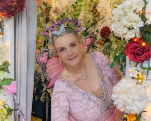 Woman dressed as a fairy godmother surrounded by flowers