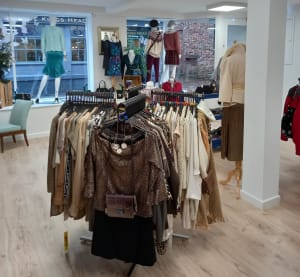A rack of brown and cream womens clothing, with female mannequins in the background.