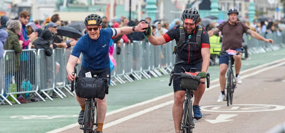 Cyclists high five as the reach the finish line of London to Brighton race