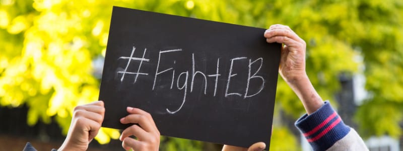Two hands holding a blackboard sign with #FightEB written on it in chalk